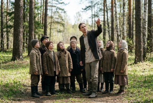 Учитель проводит в весеннем лесу урок, рассказывая ученикам о природе.